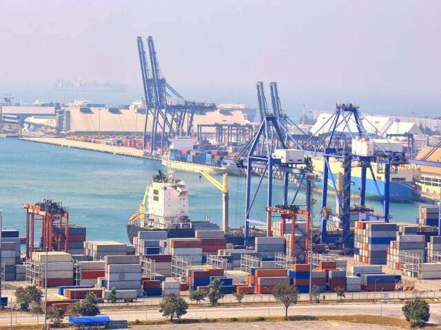 Container Cargo freight ship with working crane bridge in shipya