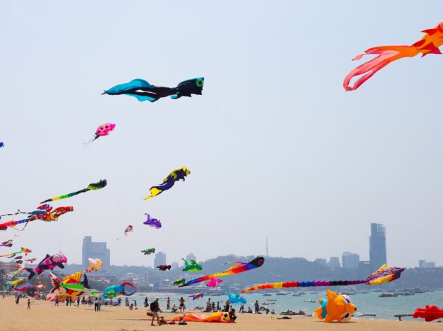 February 27, 2023  "Pattaya International Kite On The Beach 2023" Colorful kites dazzled in the sky. Many tourists enjoy to fly kites and look up. Pattaya beach, Chonburi, Thailand.