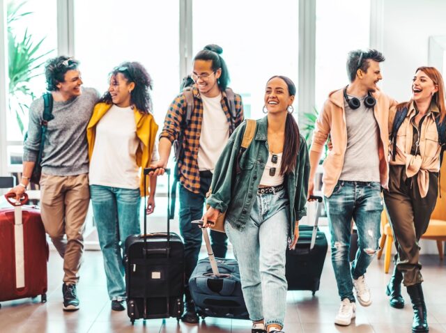 Young group of tourists with suitcases arriving at youth hostel guest house - Happy friends enjoying summer vacation together - Millenial people doing check-in at hotel lobby - Summertime holidays