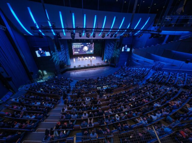 Svetlogorsk, Russia - October 18, 2023: Top view off business crowd attending international seminar in large blue illuminated auditorium at forum