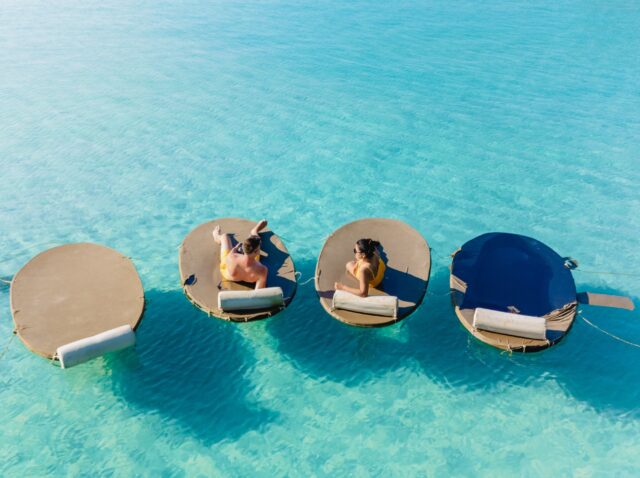 Two friends enjoy a tranquil day on floating loungers under the bright sun in the clear turquoise waters of Koh Kood. The serene atmosphere invites relaxation and fun.