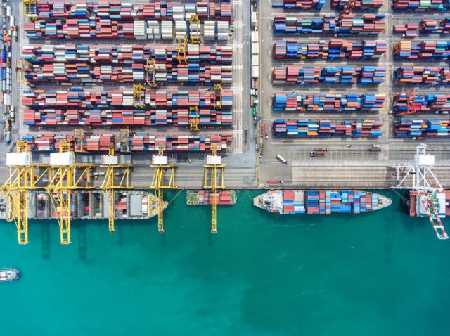 Container ship in export and import business and logistics. Shipping cargo to harbor by crane. Water transport International. Aerial view